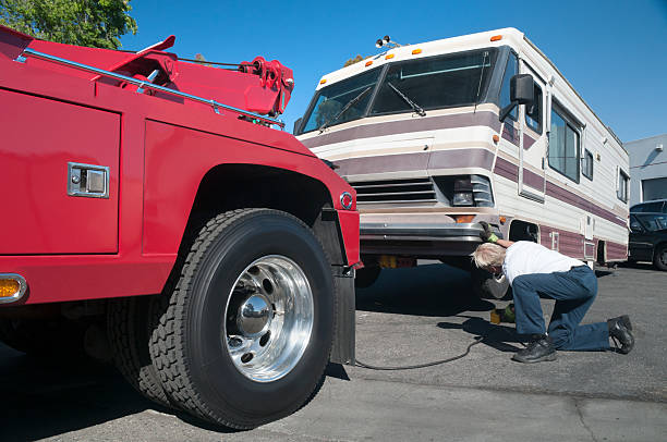 A tow truck driver preparing a broken down RV for towing.